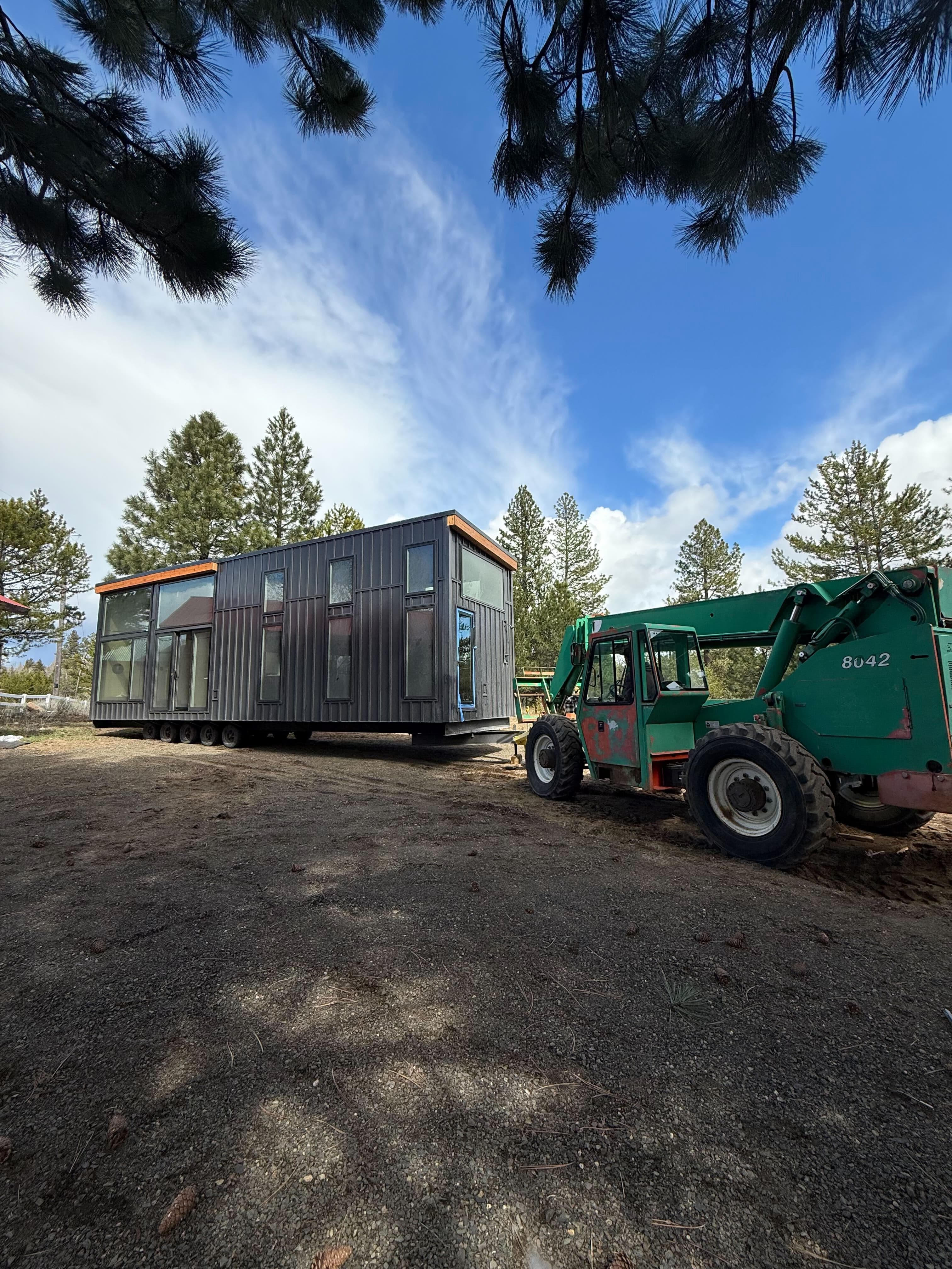 Montera Homes factory — telehandler moving a completed modular unit on site